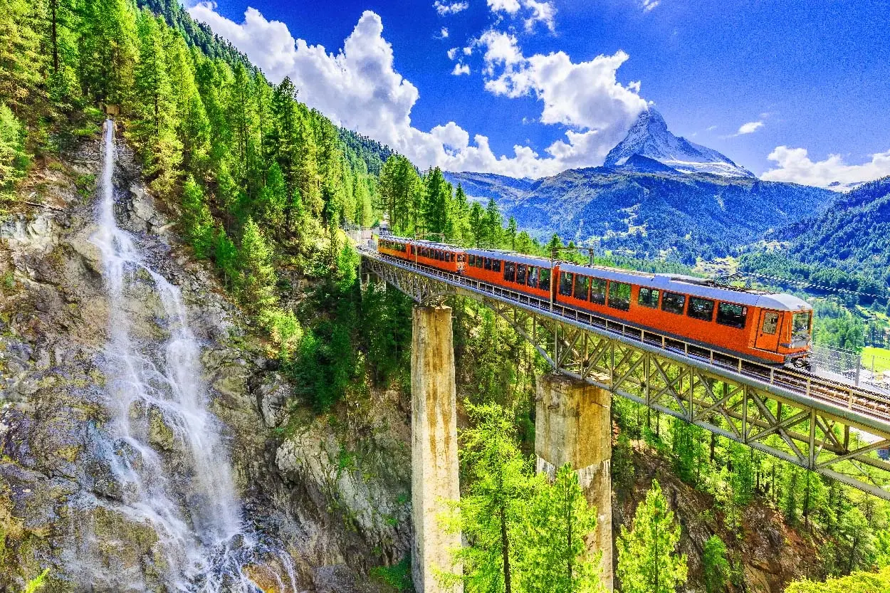 Swiss train traveling through the Alps with mountains and lakes