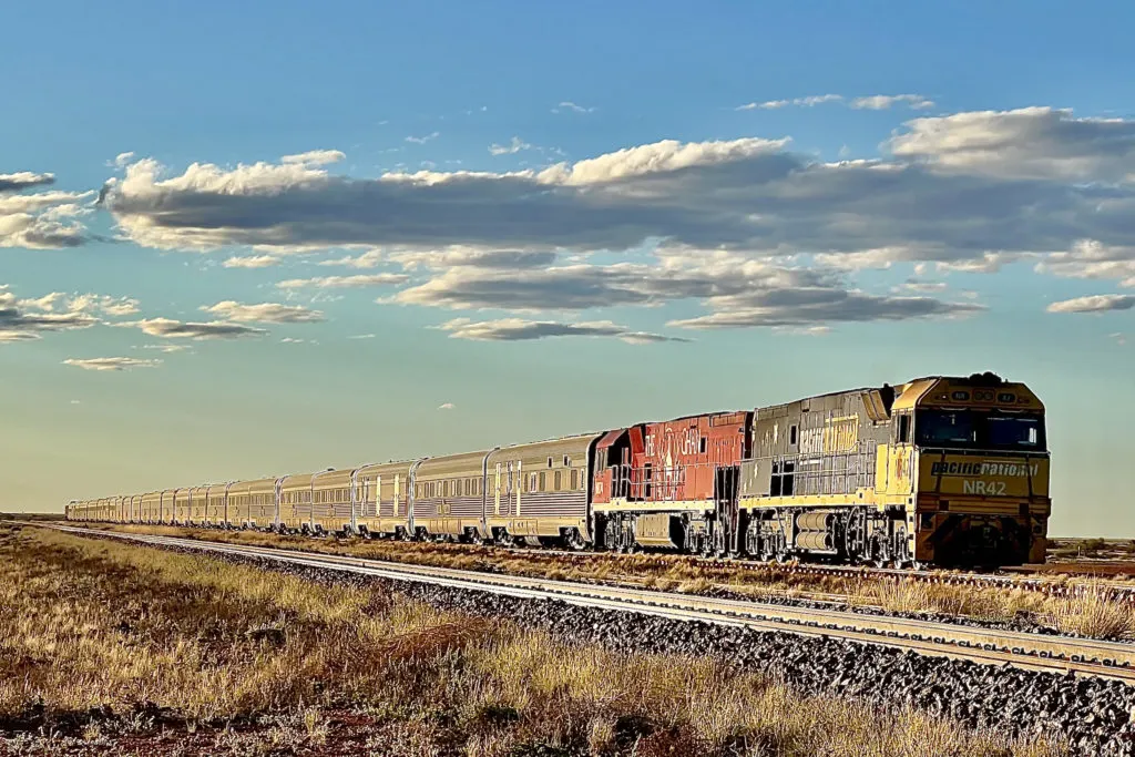 The Ghan train traveling through the red Australian outback desert